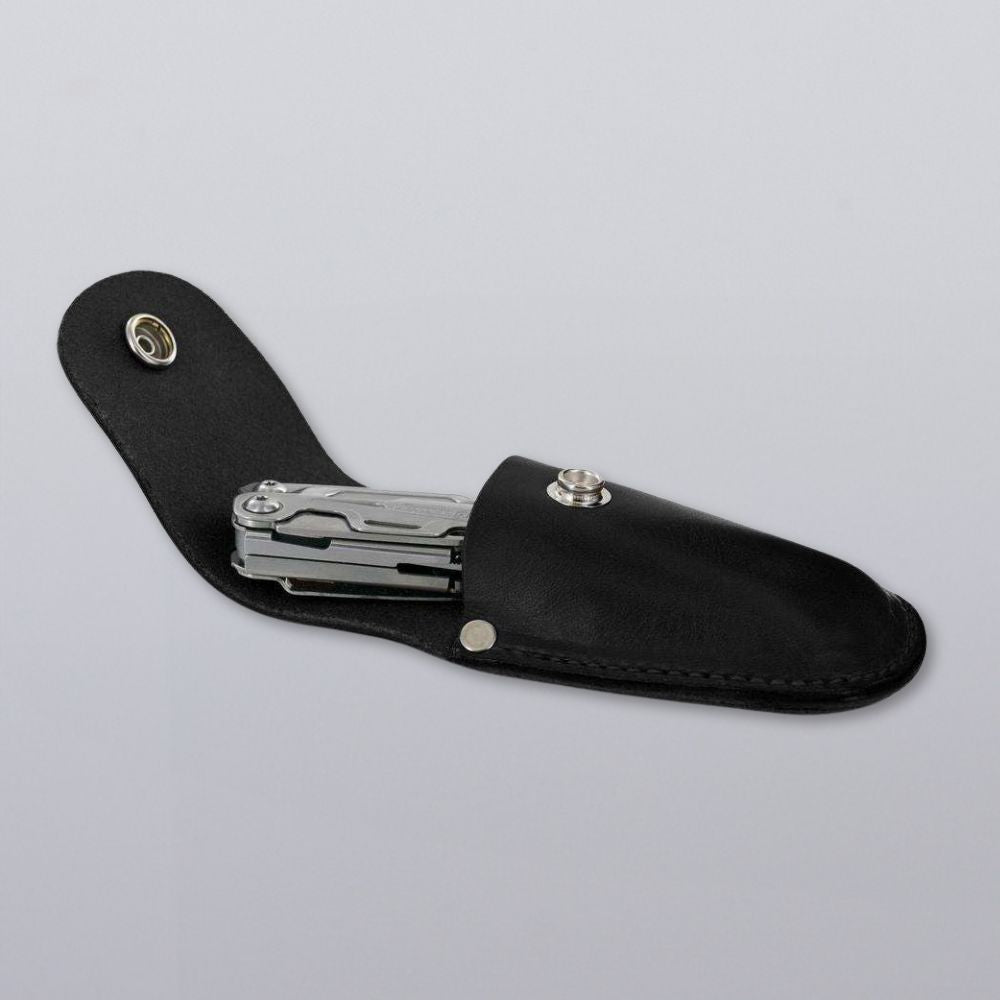 The Canyon Utility Sheath and Mag Case by Hanks Belts holds a silver multitool, partially tucked into its black bridle leather sheath with snap closure, displayed on a plain light gray background.