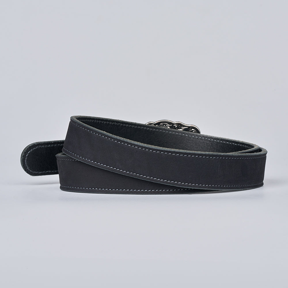 The Lennon Suede by Hanks Belts, a black leather women's belt with white stitching and a partially visible silver buckle, is coiled on a light gray background.