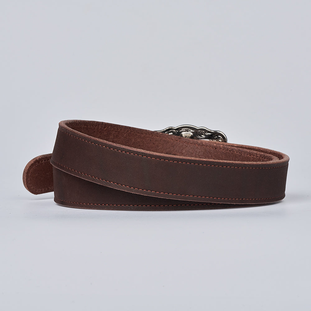The Lennon Suede by Hanks Belts—a brown women’s belt with visible stitching and a silver buckle—coiled neatly on a plain light gray background.