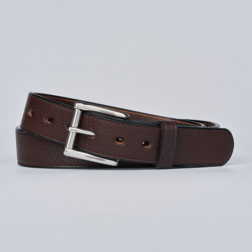 Brown leather belt with silver buckle on a light gray background