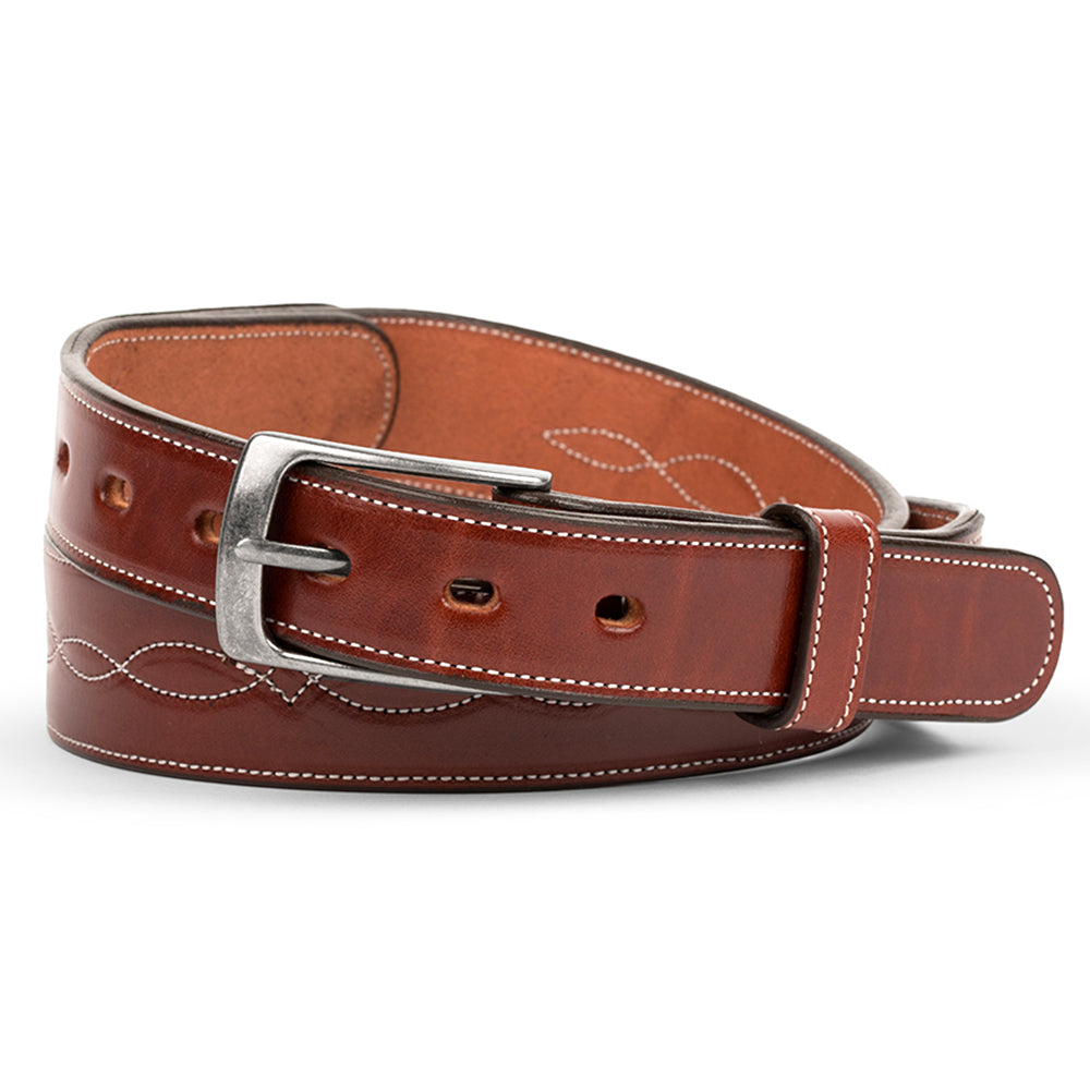 The Teton Tapered by Hanks Belts in Oak is crafted from vegetable tanned leather, features white infinity stitch detailing and a silver buckle, and is shown rolled up neatly on a white background.