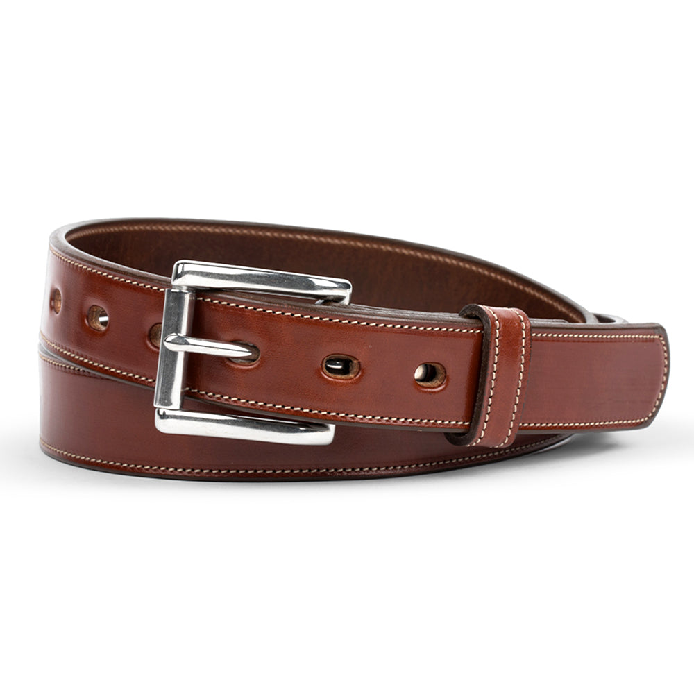 The Highland Lined by Hanks Belts is an oak-colored, vegetable-tanned leather belt with white stitching, a silver buckle, and multiple oval holes along its length.