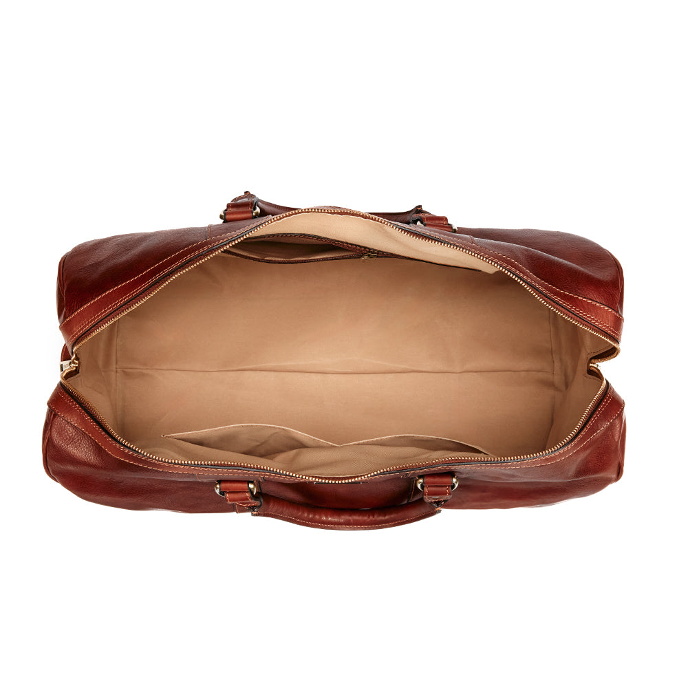 Top view of a Wanderer Duffel by Hanks, showcasing a spacious beige interior. This Italian-made luxury leather bag features two handles and brass hardware, with a zipper elegantly running along the top. 2 compartments on one side and one zip compartment on the other.