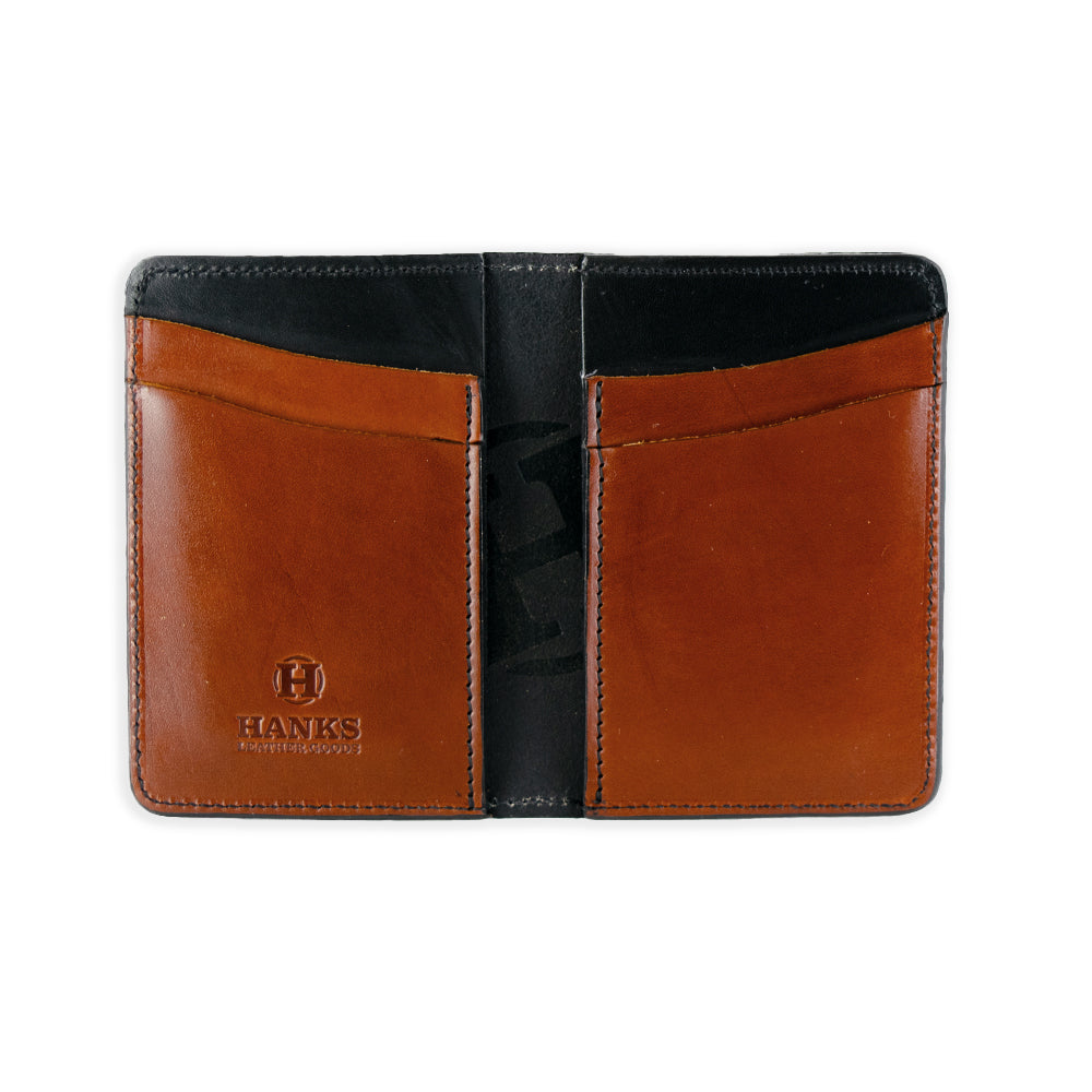 The Superior Front Pocket Bifold by Hanks Belts is a USA-made wallet crafted from premium harness leather, featuring an embossed "HANKS" logo on the bottom left with two brown pockets and a black interior.
