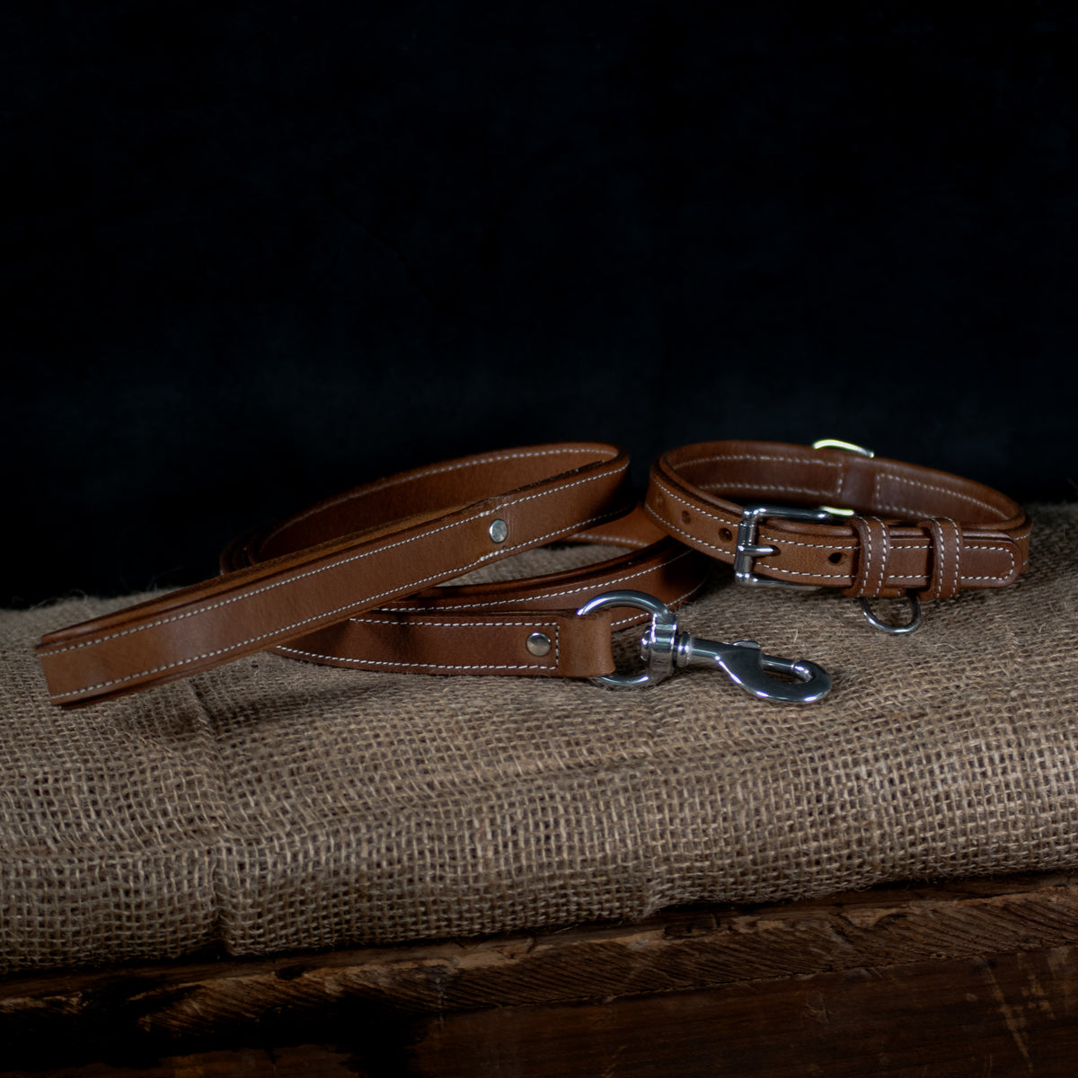The Hanks Belts Kodak Bison Leash, crafted from premium bison leather with stainless steel hardware, is displayed on burlap fabric against a dark background.