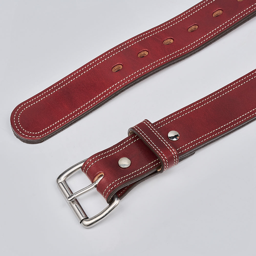 A close-up of Hanks Belts' The Premier Double Layer, a brown English bridle leather belt with white stitching, silver buckle, and multiple adjustment holes, crafted from vegetable-tanned leather on a light gray background.
