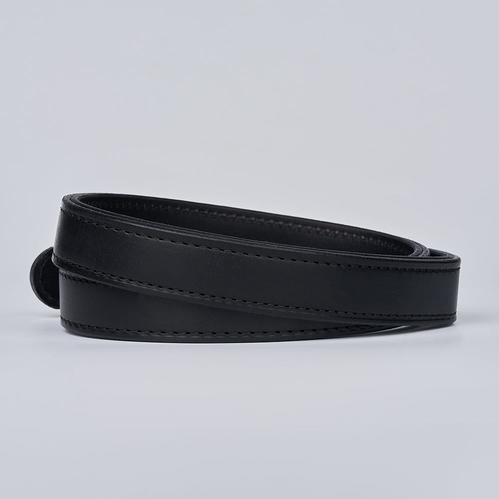 The Steel Core - 1.25" CCW belt by Hanks Belts, in black leather with edge stitching and no visible buckle, is coiled neatly on a plain light gray background.