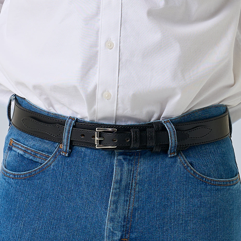 A person wears a white shirt tucked into blue jeans, finished with Hanks Belts' The Ranger—a full-grain leather belt featuring a silver buckle.