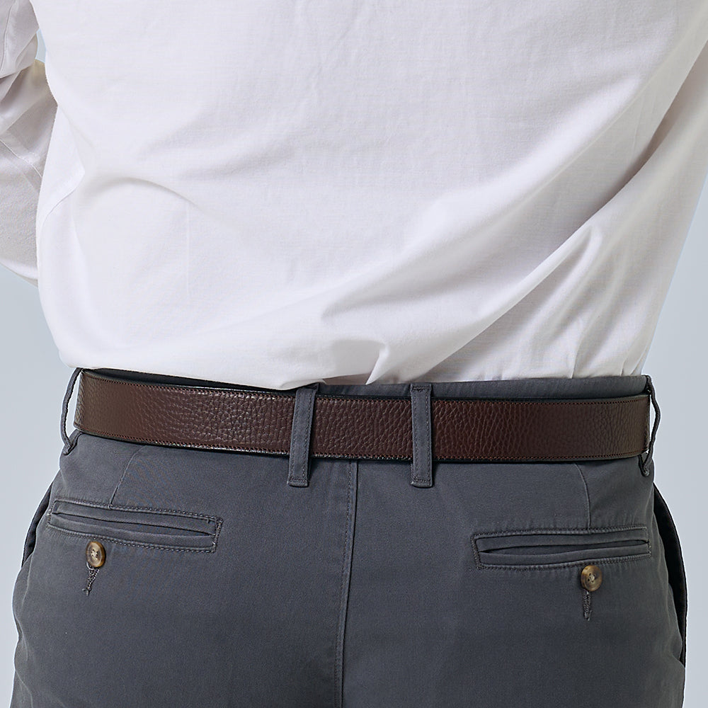 Person wearing a white shirt, gray pants, and a brown belt on a light gray background