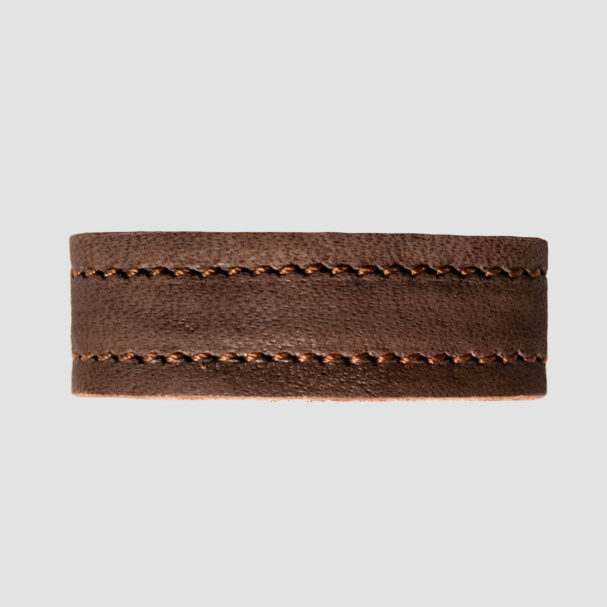 A close-up of the Hanks Belts 1.5" Suede #16 Keeper shows its brown nubuck leather band with visible stitching along the top and bottom edges, set against a plain gray background.