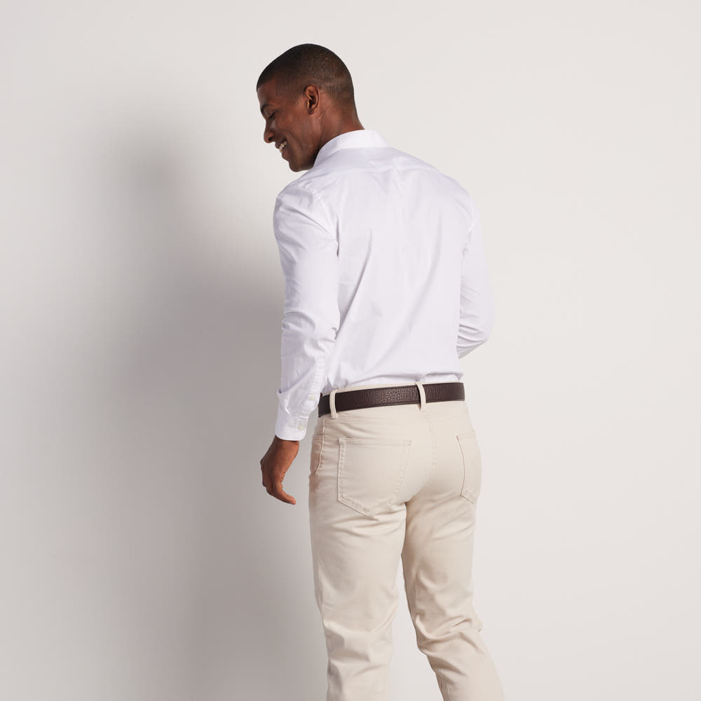 A man stands facing away in a white shirt and light beige pants, accessorized with Hanks Belts' The Tuscan Embossed Lined premium leather belt featuring a stainless steel buckle, set against a plain white background.
