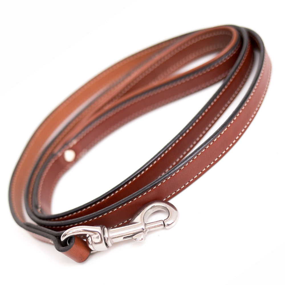 The Rover Standard Leash by Hanks Belts, crafted from brown English Bridle leather with white stitching and a silver clasp, is coiled and displayed on a white background.